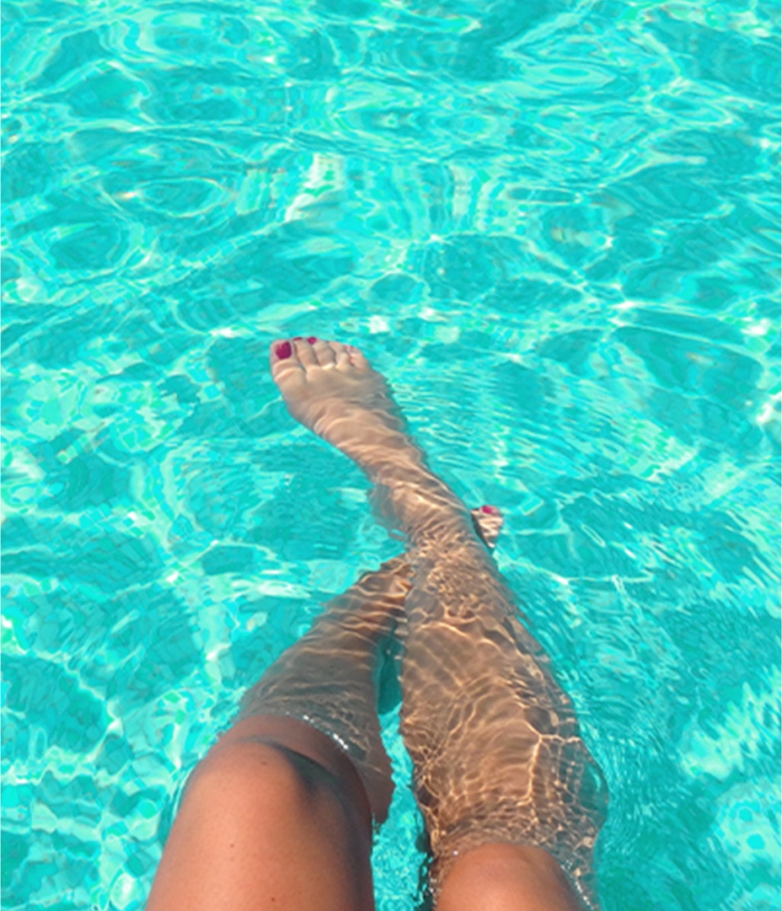 image of a pair of feet relaxing in the pool in the community pool